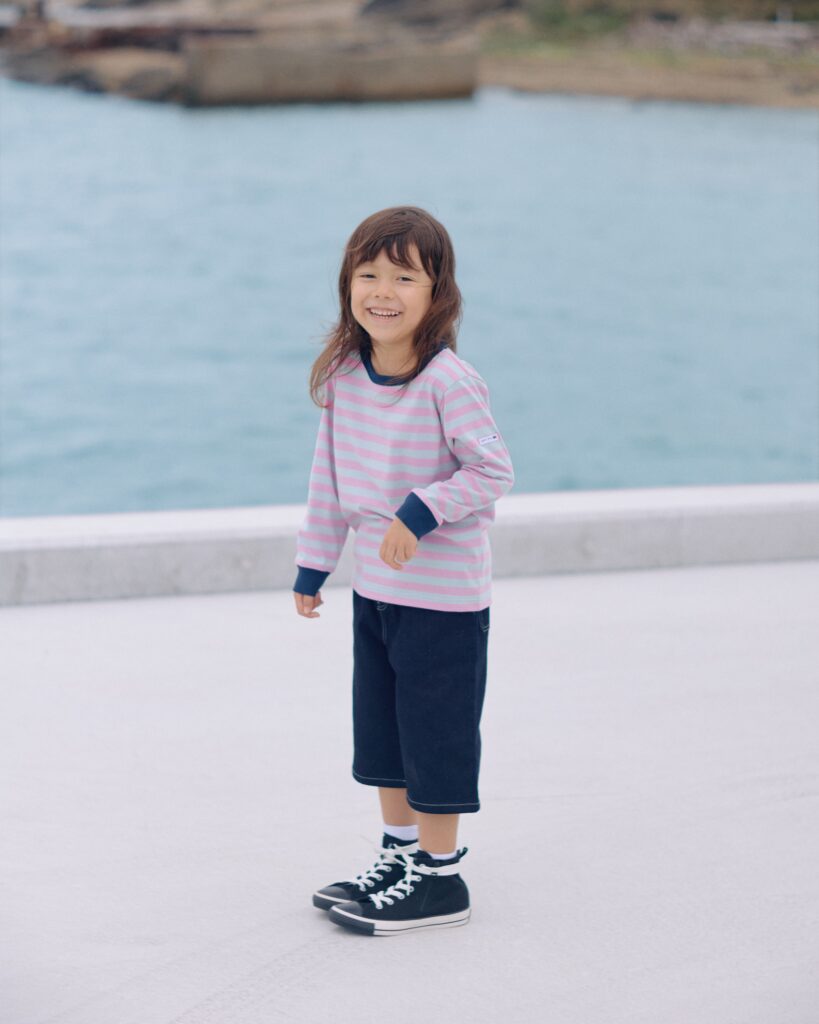 ボーダーの服を着た子供がこちらに笑顔を向けている写真